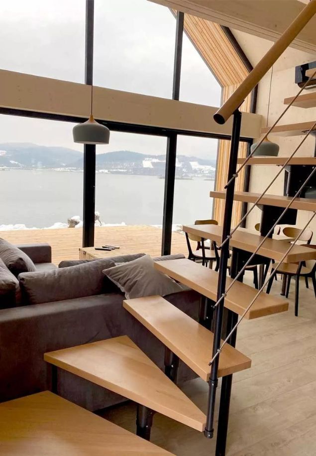 Moderna unutarnja stepeništa BOSTON s pogledom na prirodu unutarnje stepenice BOSTON s crnom metalnom konstrukcijom i drvenim gazištima u modernom dnevnom boravku s pogledom na jezero