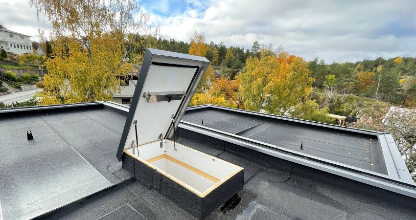 Siguran i praktičan pristup krovu – rješenje za moderne objekte s ravnim krovom otvoreni krovni izlaz s termoizolacijom na ravnom krovu kuće okružene jesenskim drvećem