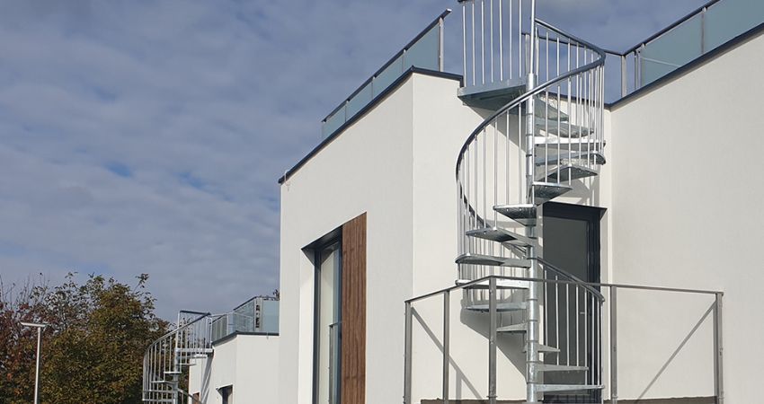 TORONTO spiralne stepenice – estetski spoj funkcije i moderne arhitekture spiralno vanjsko stubište TORONTO od pocinčanog metala montirano na balkon suvremene bijele zgrade s ravnim krovom