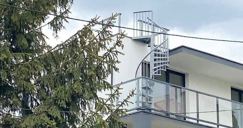 TORONTO spiralne stepenice – siguran pristup krovu bez kompromisa u dizajnu metalno spiralno stubište TORONTO montirano na gornji kat moderne kuće s ravnim krovom i staklenom ogradom