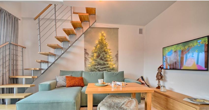 Toplina doma u svakom detalju – stubište koje nadopunjuje atmosferu modularno stubište s drvenim gazištima i čeličnim sajlama uz zid dnevnog boravka s kaučem, TV-om i božićnim dekoracijama