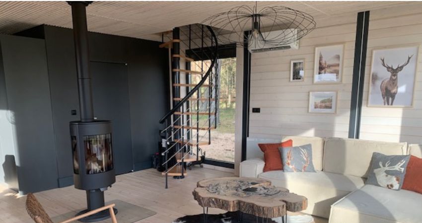 Spiralne stepenice u toplom interijeru – spoj funkcionalnosti i prirodne estetike spiralno stubište s drvenim gazištima u modernom dnevnom boravku s kaminom i velikim prozorima s pogledom na šumu