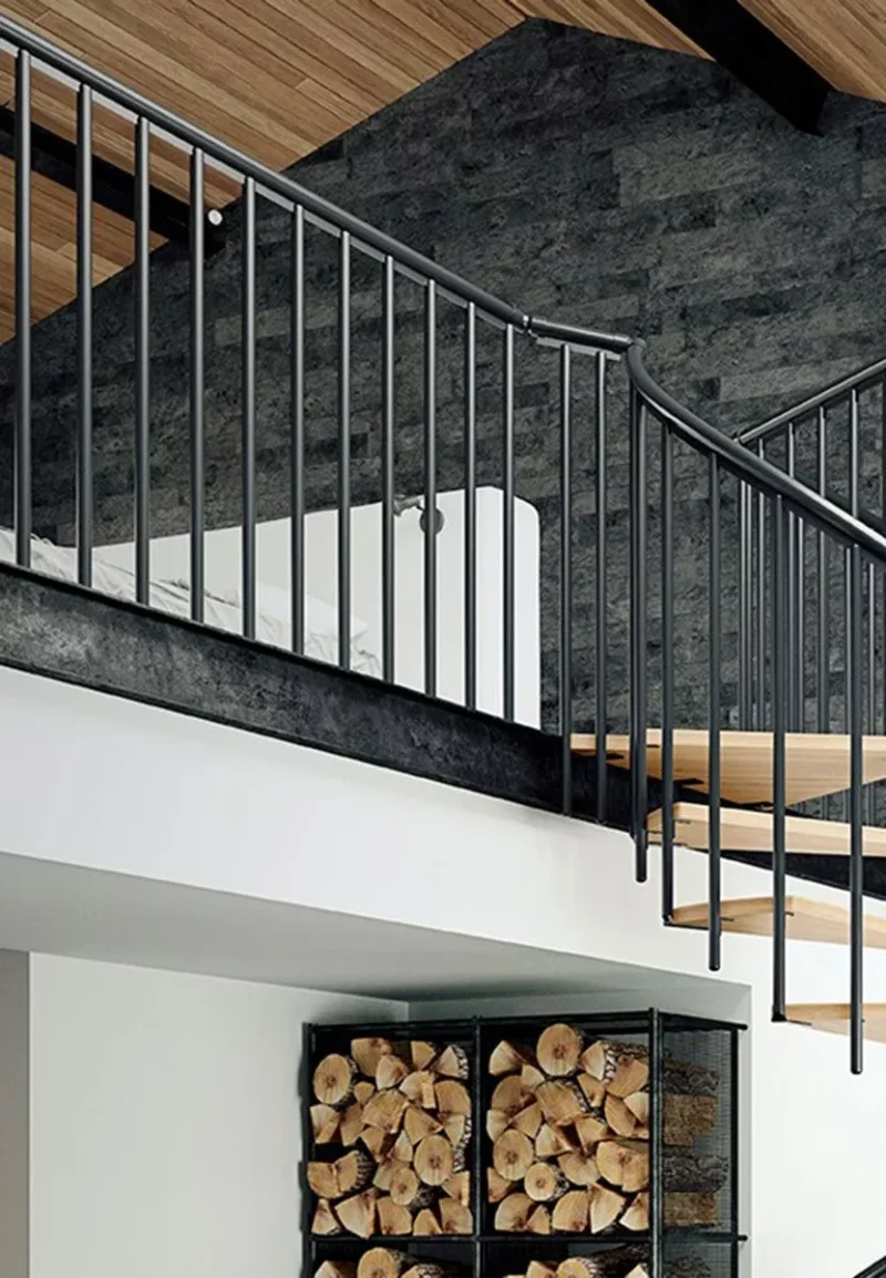 crna spiralna ograda stubišta MONTREAL u modernom potkrovlju s drvenim stropom i skladištem drva ispod galerije