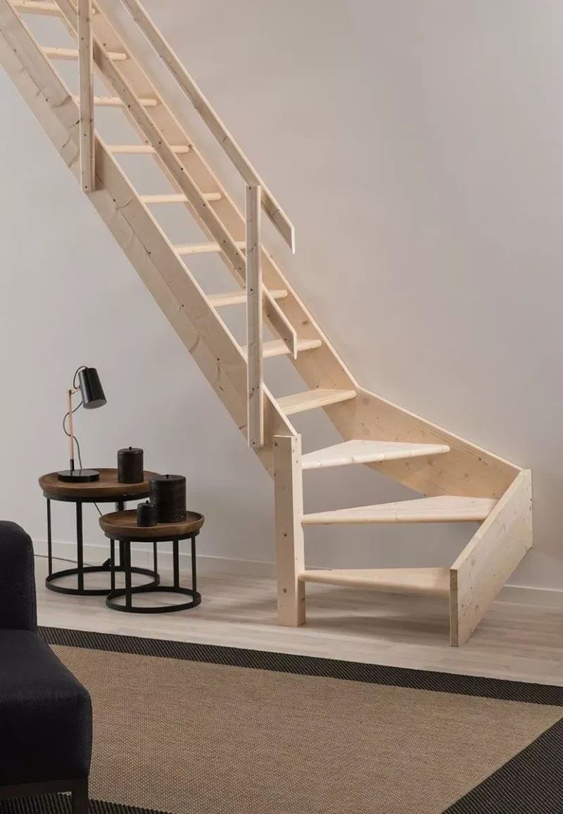 Praktičan kutni dizajn – NORMANDIE stubište štedi prostor i donosi toplinu drva u svaki interijer drveno stubište modela NORMANDIE s kutnim donjim stepenicama uz svijetli zid i dekorativne stoliće