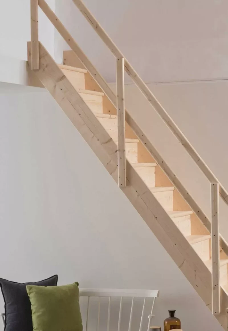 Masivne i stabilne – NORMANDIE stubište za svakodnevnu udobnost u prirodnom drvu drvene stubišne stepenice modela NORMANDIE s bočnom ogradom uz bijeli zid i ukrasne jastuke ispod