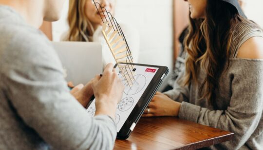 tim DOLLE analizira 3D model stepenica na tabletu tijekom sastanka