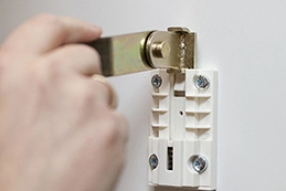 ruka montira metalni nosač u plastični držač vijcima na bijeli zid