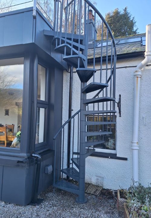 Antracitno spiralno stubište DOLLE TORONTO koje vodi s terase u vrt uz modernu obiteljsku kuću